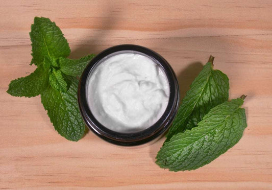 Open jar of Maxwell & McIntyre SLS-free Sweet Peppermint coconut toothpaste with fresh mint leaves